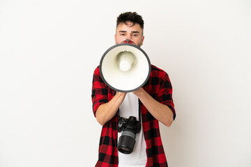 Young photographer caucasian man isolated on white background shouting through a megaphone