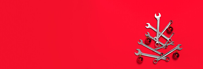 Christmas tree made of wrenches decorated with balls on red background. Happy New Year banner with...