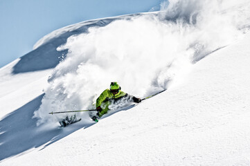 Skier rides in the mountain against the blue sky on fresh snow