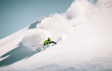 Skier rides in the mountain against the blue sky on fresh snow - obrazy, fototapety, plakaty