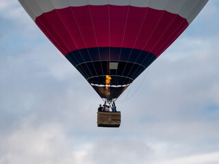 Hot air balloon with basket flying in the sky