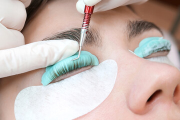 Young woman doing eyelash lamination procedure in a beauty salon