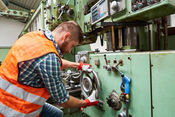 Arbeiter in Fabrik bedient Standbohrmaschine an Rad