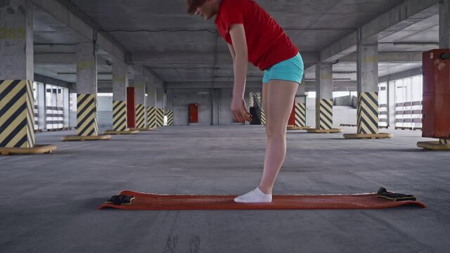 Young girl stands on yoga mat and bends to her toes to stretch posterior of hamstrings. Important part ofo any phisical training