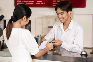 woman guest write signature for check in hotel from receptionist on tablet