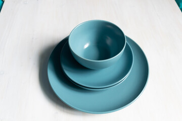 empty blue-green  crockery like plates and bowl on white  table