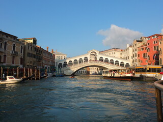 The Historic Rialto Bridge Ponte di Rialto above the Famous Canale Grande with a Vaporetto in Italy´s Venice - obrazy, fototapety, plakaty