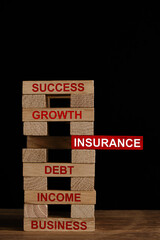 Red insurance wooden block in the middle of business related words on other wooden blocks.