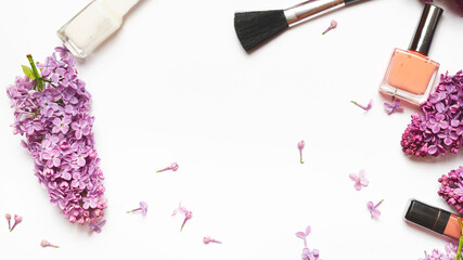 Beauty concept. Blogger or freelancer round workspace with cosmetics, branches of lilac and accessories on white background. Flat lay, top view.