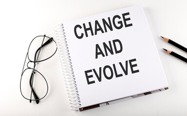 Notebook with text Change and Evolve on white background