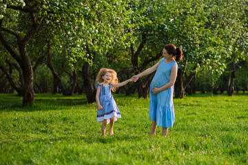 Naklejka na ściany i meble nature scene with family outdoor lifestyle. Mother and little daughter playing together in a park. Happy family concept. Happiness and harmony in family life.