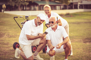 Senior golfers on court. Two men using smart phone.