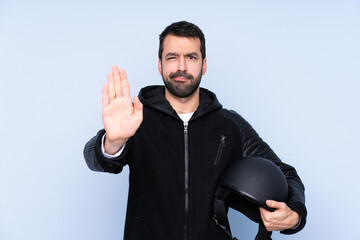 Fototapeta premium Man with a motorcycle helmet over isolated background making stop gesture