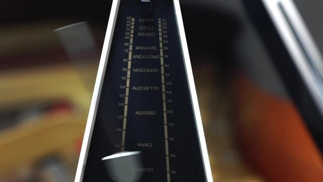 Metronome with pendulum fast in motion, to keep rhythm and tempo for piano, classical music,  musicians - close-up with selective focus