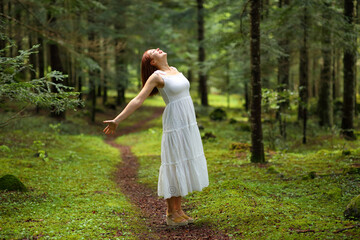 Woman in white dress celebrating in a green forest