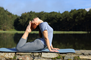 Fototapeta na wymiar Woman practicing yoga pose in a lake in the mountain