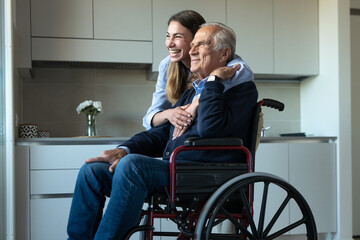 Cinematic shot of happy granddaughter hugging grandfather in wheelchair as sign of love and respect...