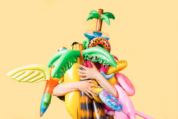 unknown person hugging a lot of pool inflatables of different shapes and colors.