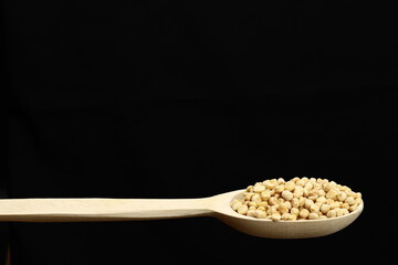 dried peas in wooden spoon on black background. Copy space for text
