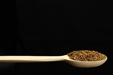 Buckwheat in a wooden spoon on a black background