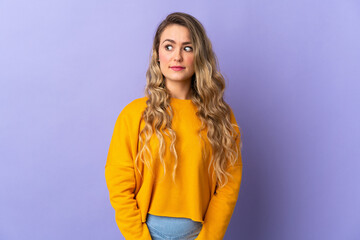 Young Brazilian woman isolated on purple background making doubts gesture looking side