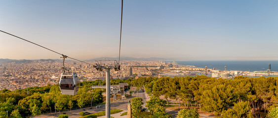 Fototapeta na wymiar Panoramic view over modern and old districts in historical downtown of Barcelona, Spain, and Barcelona Cable Car system, cityscape, at summer sunset colors.