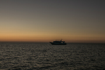 Fototapeta na wymiar Red sunrise sky at sea and silhouettes of ships sailing on the sea.