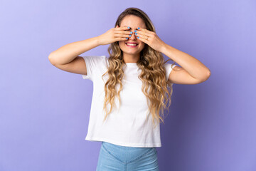 Young Brazilian woman isolated on purple background covering eyes by hands and smiling