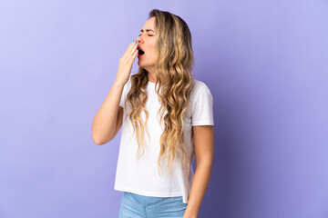 Fototapeta premium Young Brazilian woman isolated on purple background yawning and covering wide open mouth with hand