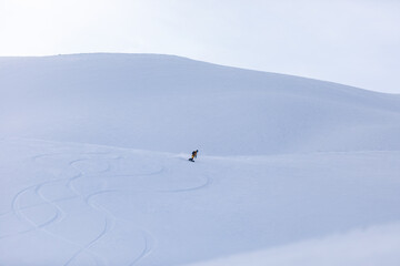 Snowboarder rides through snowy mountains on heliskiing