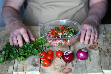 The cook prepares raw minced meat for the barbecue. The cook mixes the minced meat and adds spices.