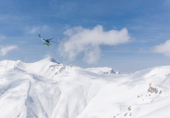 Helicopter flies into bare sky against snow mountains