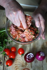 The cook prepares raw minced meat for the barbecue. The cook mixes the minced meat and adds spices.