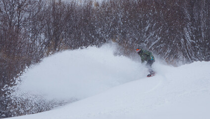 Сноубордист пускает спрей из снега в горах зимой