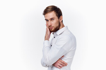 handsome young man in shirt touches his face with hand side view light background