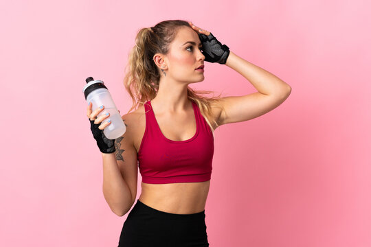 Young Brazilian woman isolated on pink background with sports water bottle © luismolinero