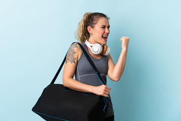 Young sport Brazilian woman with sport bag isolated on blue background celebrating a victory