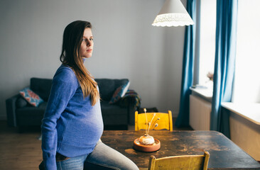 pregnant woman stands at a table in an apartment