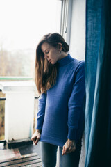 pregnant woman stands by the window in an apartment