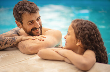 Fototapeta premium Father and daughter having talk in swimming pool.
