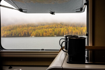 Camping Pause Kaffee Tee Tasse mit Blick aus dem Fenster auf See und herbstlichen Wald