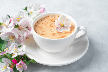 Obraz na płótnie Canvas White coffee cup and flowers close-up on a gray background.