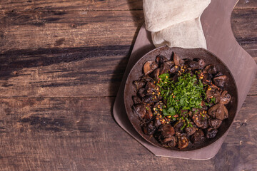 Fried royal champignons in an old cast-iron skillet with trendy hard light, dark shadow