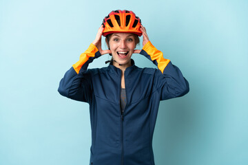 Young cyclist woman isolated on blue background with surprise expression - obrazy, fototapety, plakaty