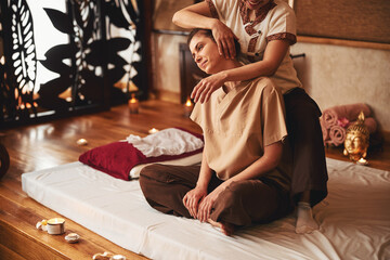 Massage professional tilting female client head to right