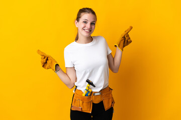 Young electrician woman isolated on yellow background pointing finger to the laterals and happy - obrazy, fototapety, plakaty