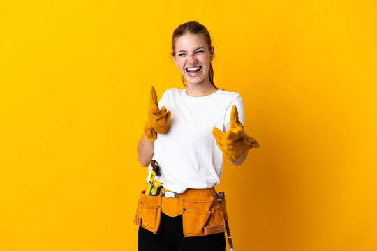 Young electrician woman isolated on yellow background pointing to the front and smiling