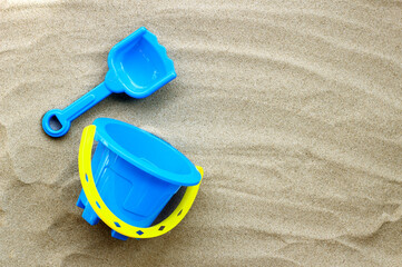 Fototapeta na wymiar Plastic toys, shovel and bucket on sand. Summer background concept