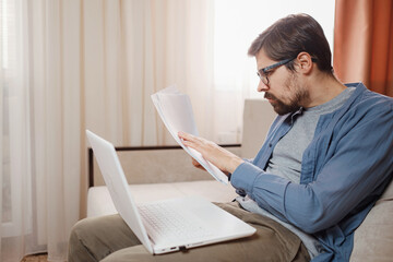 Entrepreneur works with a laptop and keeps a document in a home office