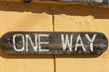 Wooden sign on the wall that says 'one way' is not a trademark close-up